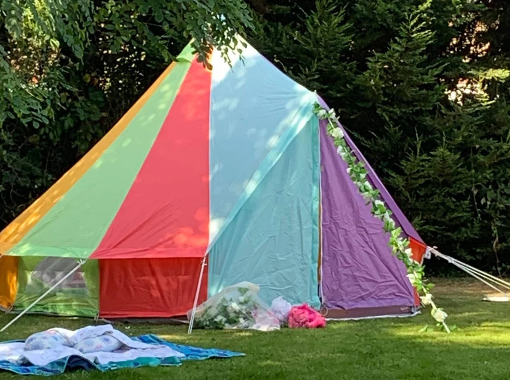 Colourful striped bell tent set up in a garden